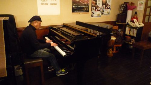 24年間続いている、ピアノの生演奏。毎週、木曜と金曜の夜は弾き語りを楽しみながら、食事とお酒を楽しむことができる(演奏者:髙橋一郎)